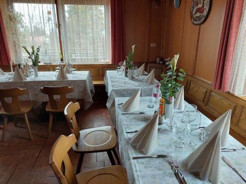 een eetkamer met lange tafels met witte tafelkleden bij Albergo Scoiattolo in Tret