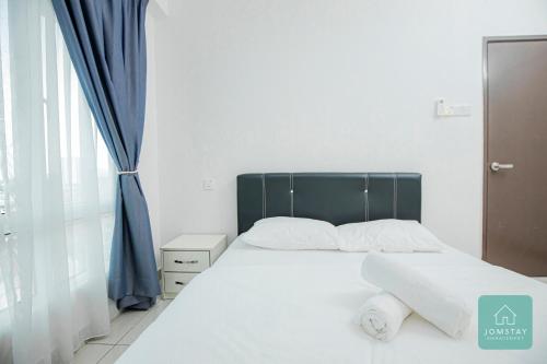 a bedroom with a white bed with a blue curtain at JOMSTAY Majestic Ipoh Suites in Ipoh