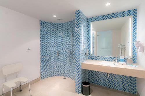 a blue tiled bathroom with a sink and a mirror at Holiday Inn Express Baruna by IHG in Kuta