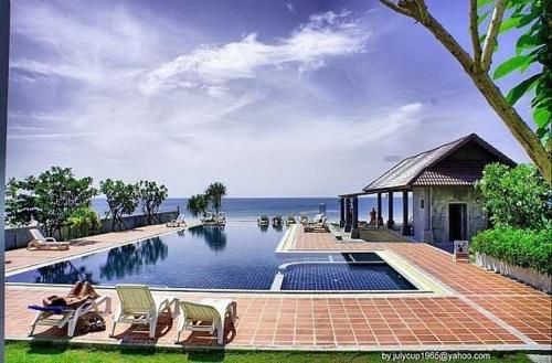 una piscina con sedie e l'oceano sullo sfondo di Khanom Beach Residence 1-bedroom Mountain & Sea View a Khanom