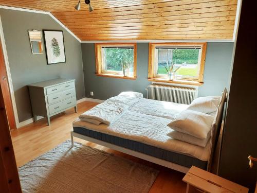 a bedroom with a bed and two windows at Nice holiday home with a view of lake Asnen in Hulevik, Lonashult in Lönashult
