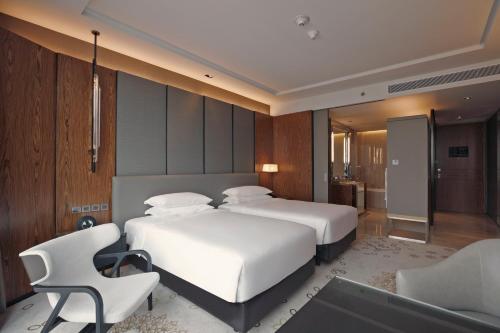 a bedroom with two beds and a desk and chair at Hyatt Regency Bangkok Sukhumvit in Bangkok