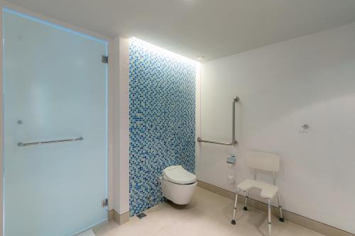 a bathroom with a toilet and a blue tiled wall at Holiday Inn Express Baruna, an IHG Hotel in Kuta