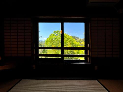 an open window in a dark room with a view at Guest House Shimoze Agematsu in Iida