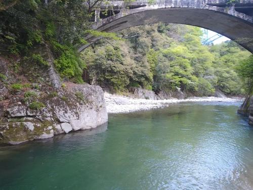 a bridge over a river with green water at Guest House Shimoze Agematsu in Iida