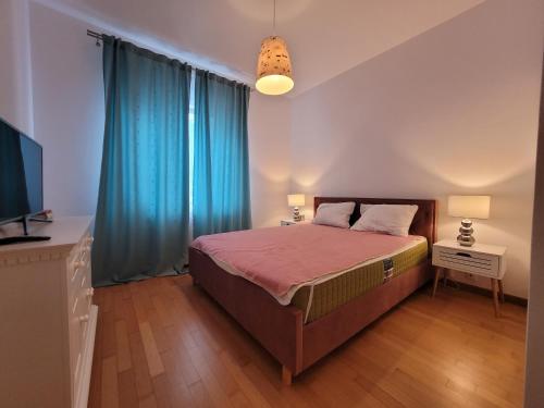 sypialnia z łóżkiem z niebieskimi zasłonami i telewizorem w obiekcie Sea Home Neptun w Neptunie