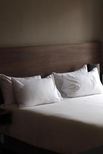 a bed with white pillows and a wooden headboard at 27 on Gunn Street in Bloemfontein