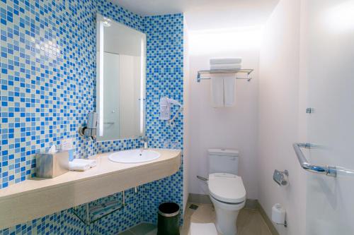a blue tiled bathroom with a toilet and a sink at Holiday Inn Express Baruna by IHG in Kuta
