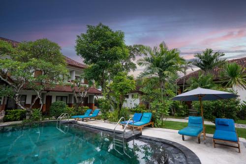 a swimming pool with blue chairs and an umbrella at Sinar Bali Hotel in Legian