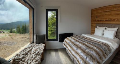 a bedroom with a large bed and a large window at Heaven`s cabins in Tău Bistra