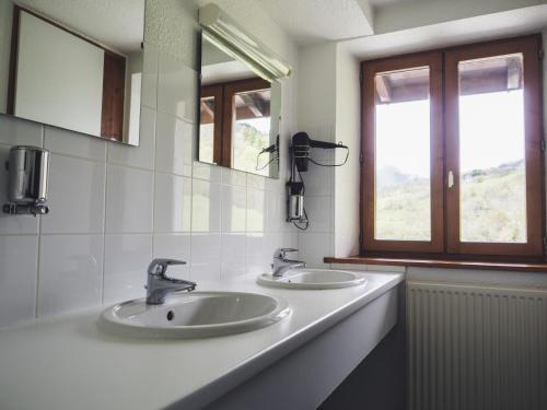 uma casa de banho com 2 lavatórios e um espelho em Auberge Le Valezan em Valezan