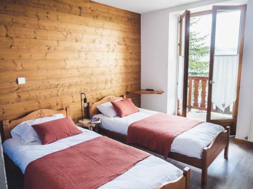 two beds in a room with a wooden wall at Auberge Le Valezan in Valezan