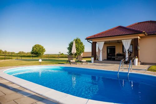 a swimming pool in front of a house at Holiday House Drava Relax in Pitomača