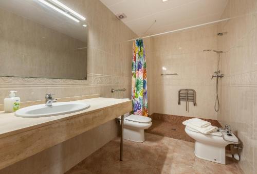 Un baño con lavabo, inodoro y espejo. en Malgrat, en Malgrat de Mar