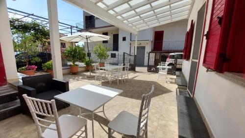 een terras met tafels, stoelen en een parasol bij Olimpo degli Dei in Agerola