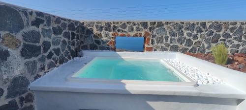 a swimming pool in a room with a stone wall at Alios private villa in Imerovigli