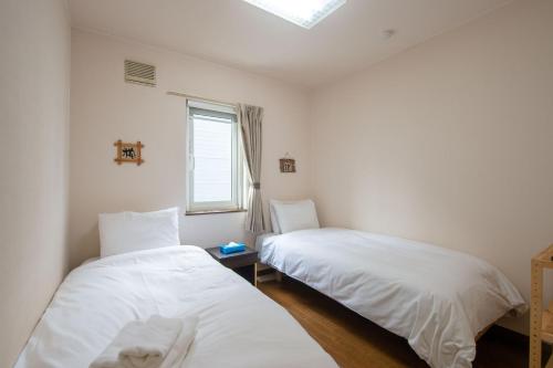 two beds in a room with a window at Asuka Value Apartments in Kutchan