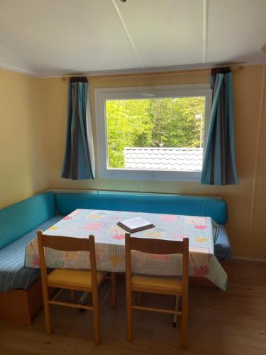 une petite chambre avec une table, des chaises et une fenêtre dans l'établissement Joli Mobil-home climatisé entièrement équipé, sauf draps en option, pour 4 adultes au maximum avec possibilité de 2 enfants en plus, à Sarlat-la-Canéda