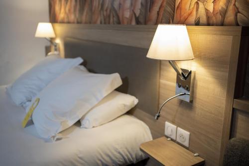 una camera d'albergo con letto, lampada e cuscini di Golden Tulip Troyes a Barberey-Saint-Sulpice