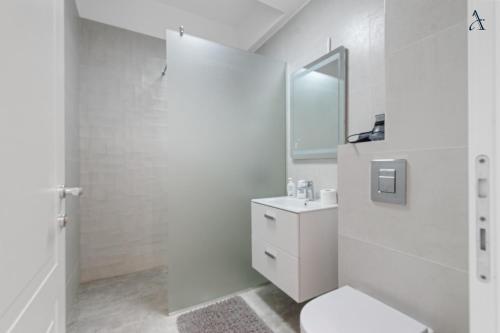a white bathroom with a toilet and a sink at RentForComfort Saint George Studio & Sea View in Mamaia