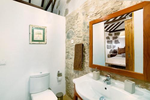 ein Badezimmer mit Waschbecken, Toilette und Spiegel in der Unterkunft La casa nueva in Fataga
