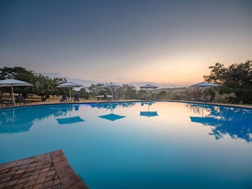 a large swimming pool with a sunset in the background at Nkambeni Safari Camp in Hazyview