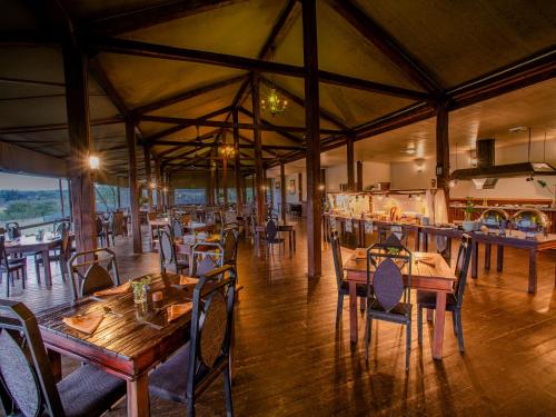 a restaurant with wooden tables and chairs in a room at Nkambeni Safari Camp in Hazyview