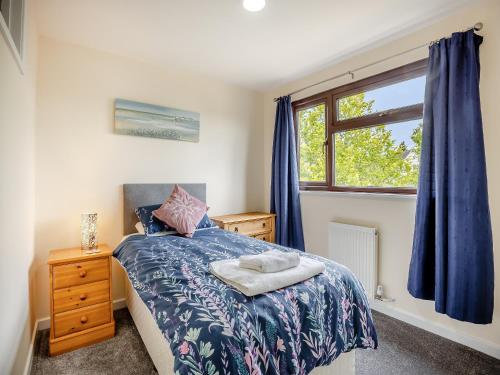 sypialnia z łóżkiem i oknem z niebieskimi zasłonami w obiekcie Casa Mia w mieście Terrington Saint John