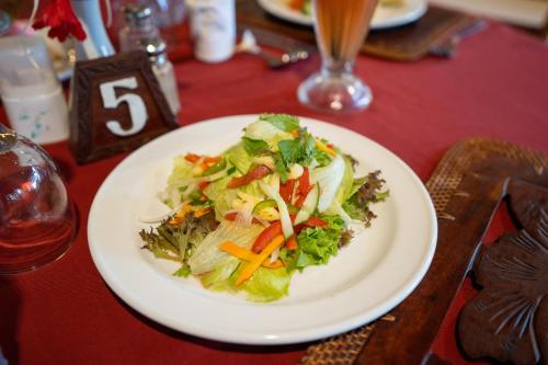 a white plate with a salad on a table at Hotel Sinar Bali Legian in Legian