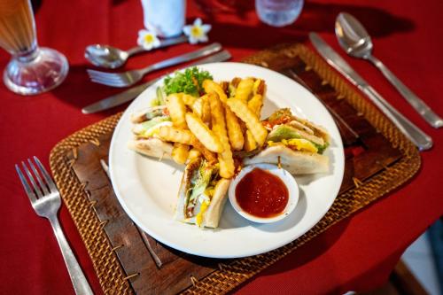 a plate of food with a sandwich and french fries at Hotel Sinar Bali Legian in Legian