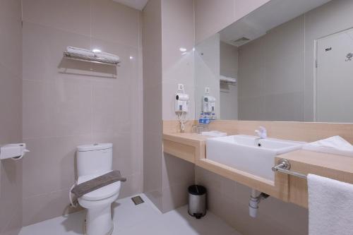 a bathroom with a sink and a toilet and a mirror at Premiere Hotel Tegal in Tegal