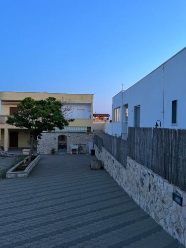 a building with a fence and a tree in a courtyard at casa in spiaggia in Marina di Pescoluse