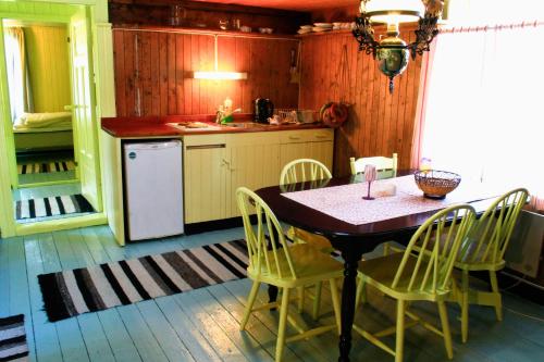 a kitchen with a table and chairs in a kitchen at Kræmmervika Rorbuer - Rustic Cabins & Hostel in Lofoten in Ballstad