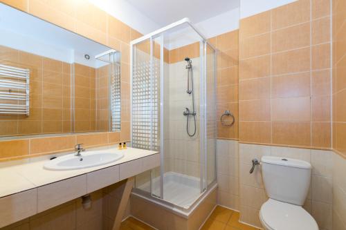 a bathroom with a toilet and a shower and a sink at Centrum Zdrowia i Wypoczynku Jantar in Darłówko