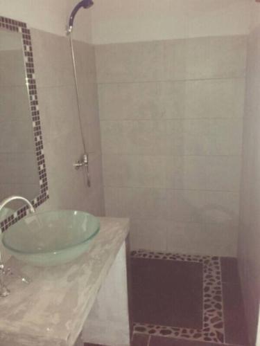 a bathroom with a glass sink and a shower at Hôtel chez Pat in Nosy Be