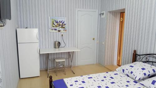 a bedroom with a bed and a table and a refrigerator at Guest House Gorny Ruchei in Gagra