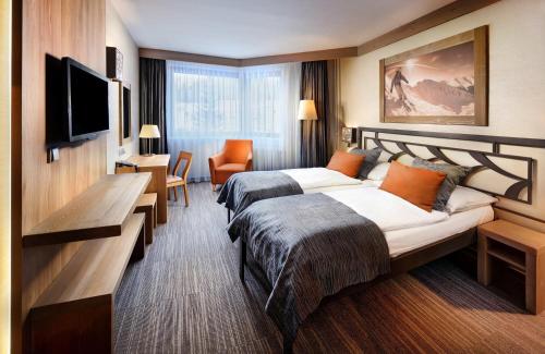 pokój hotelowy z 2 łóżkami i telewizorem z płaskim ekranem w obiekcie Hotel Grand Jasna w Demianowskiej Dolinie