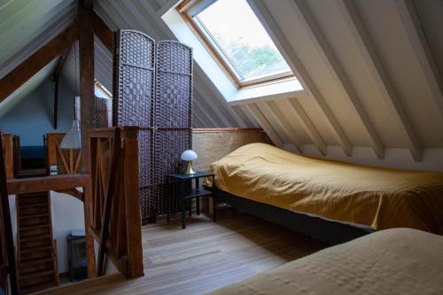 1 dormitorio en el ático con 2 camas y ventana en Gîte de l'Ecrin de l'Andelle - Forêt de Lyons, 