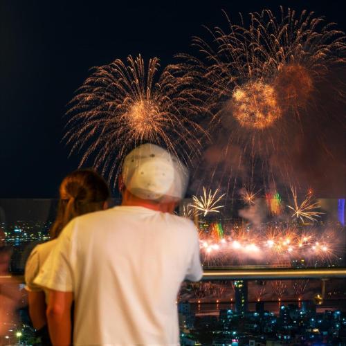 a man looking at fireworks in the sky at Luxury Apartment - Rooftop Swimming Pool - Beach Front - Hinata Apartment in Da Nang