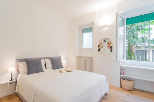 a white bedroom with a large white bed and a window at A Step from the Lake Apartment by Rent All Como in Como
