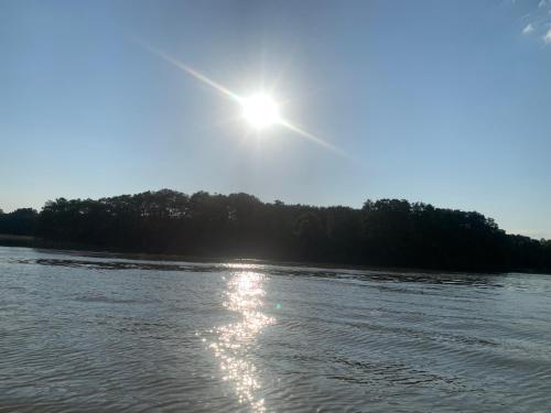 a sun shining over a river with trees in the background at MAŁY PORT-Iława - Jezioro - Plaża - Marina priv - 5 pokoi VIP - czysto na 10 in Iława