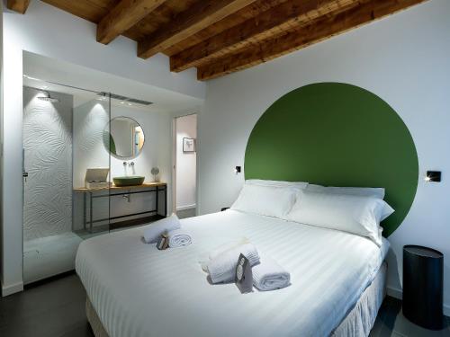 a bedroom with a large white bed with a green headboard at SG9 CITY APARTMENTS in Brescia