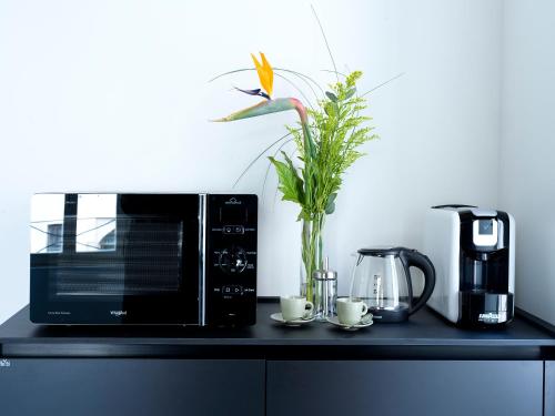 a black counter with a microwave and a vase with a flower at SG9 CITY APARTMENTS in Brescia