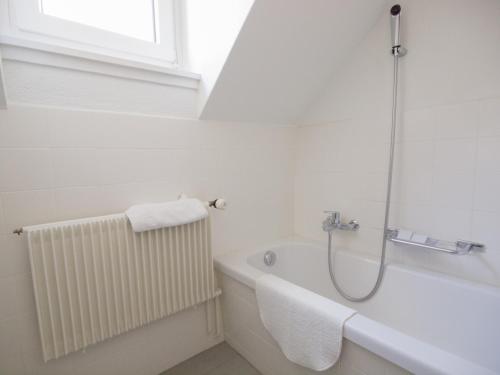 a white bathroom with a bath tub and a window at Hotel Gregory in Zürich