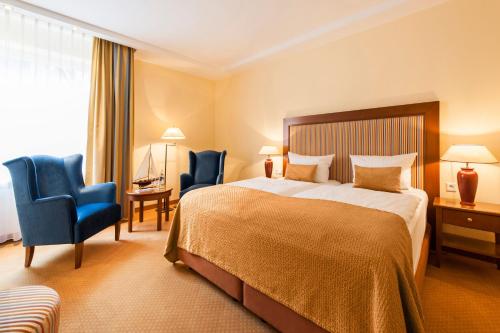 a hotel room with a bed and two blue chairs at Hotel Birke, Ringhotel Kiel in Kiel