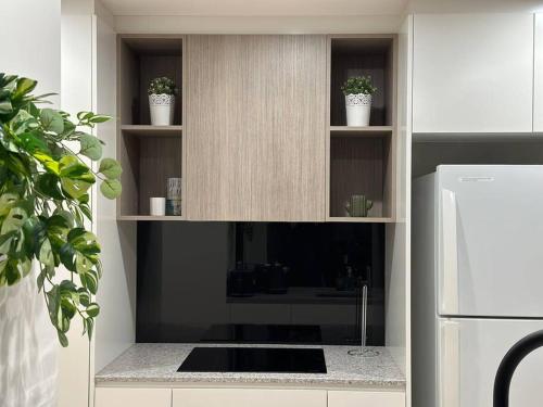 a kitchen with a counter with shelves and a refrigerator at Cityscape Lovely 1BR Apt & Parking @CBD in Canberra