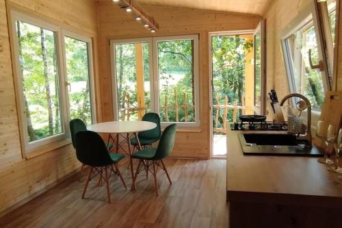a kitchen with a table and chairs and windows at Treehouse LEA in Mikulášovice
