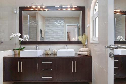 uma casa de banho com 2 lavatórios e um espelho grande em Villa Harvey em Albufeira