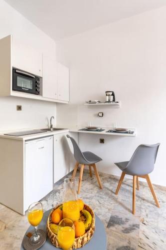 a kitchen with a bowl of oranges and two chairs at Dora Apartment in Áyios Andónios