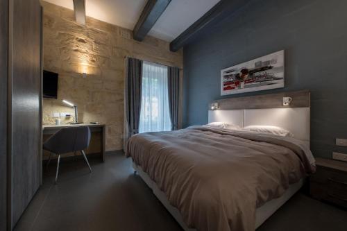 a bedroom with a bed and a desk and a window at Harbour Haven Maisonette in Kalkara
